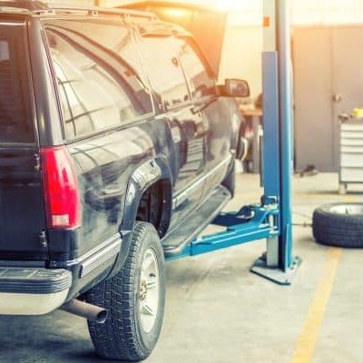 Old rusty offroad SUV vehicle raised on lift at maintenance station. Automobile repair and check up. Old rusty offroad SUV vehicle raised on lift at maintenance station. Automobile repair and check up.